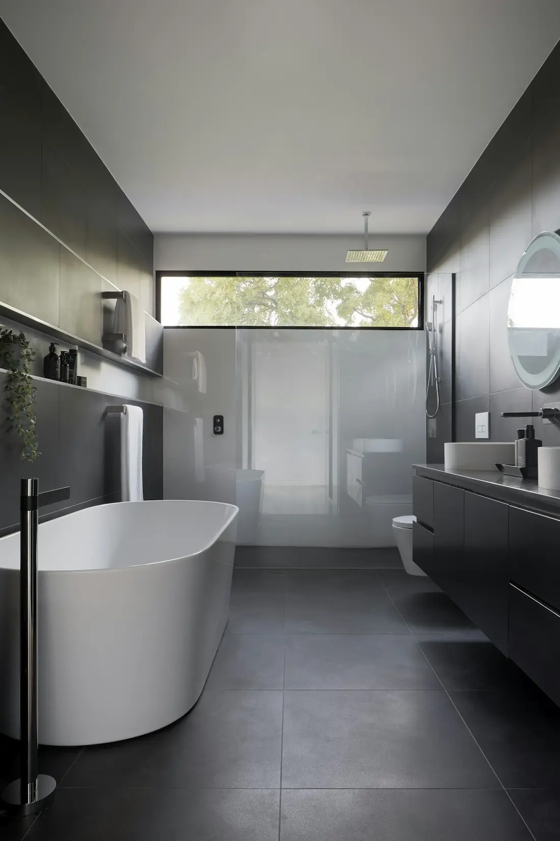 Dark tiled bathroom with a freestanding tub and a clerestory window